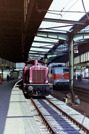 Eine rote Diesellok (211 084) steht in Duisburg Hbf an Gleis 4 zur Fahrt nach Kleve.
